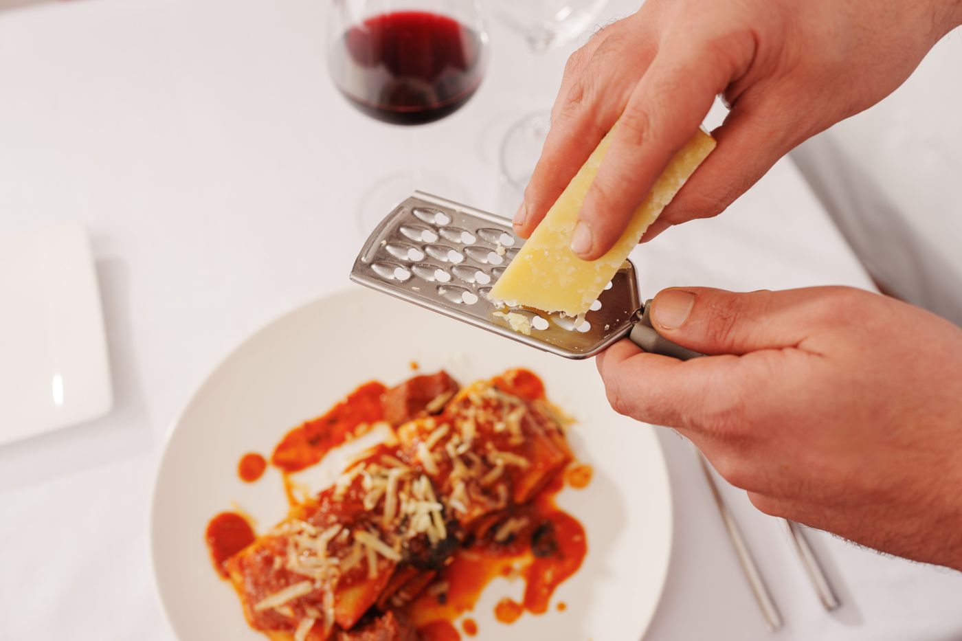 Le parmesan râpé à la main sur une assiette de pâtes
